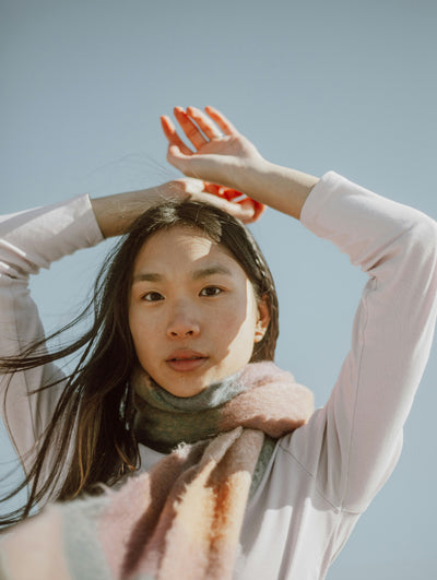 Woman looking at camera with scarf on against blue sky